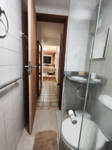 a bathroom with a toilet and a glass door at Temporada Beira-Mar Maceió in Maceió