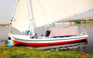 a sail boat in the water with people on it at Felucca Sailing Boat Overnight Experience in Aswan