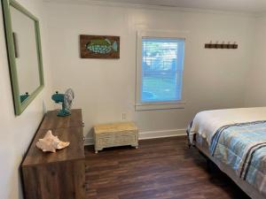 a bedroom with a bed and a dresser and a window at The Cottage in Wilmington