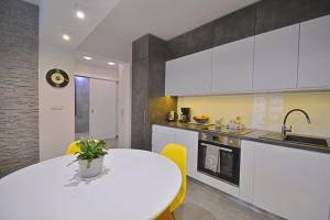 a kitchen with a white table and yellow chairs at Apartamenty Bryza - Debina in Świnoujście