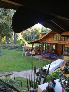 a log house with people sitting in the yard at Valle el Abra Ralún Lodge in Puerto Varas