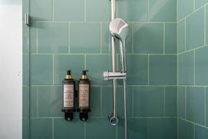 a shower with two shampoo bottles on a tiled wall at Firmeza388 Charming Flats in Porto