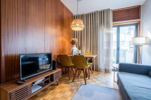 a living room with a television and a table with chairs at Firmeza388 Charming Flats in Porto