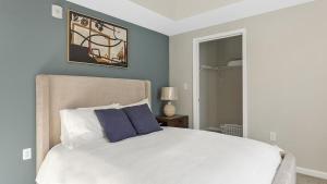 a bedroom with a white bed with blue walls at Landing Modern Apartment with Amazing Amenities (ID1264X851) in Richmond