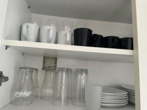 a shelf with glass jars and plates on it at Beautiful and luxurious 4-Bed House in Essex in Stanford-le-Hope