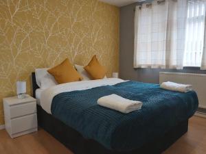 a bedroom with a bed with two towels on it at Luxurious Beautiful Home Ideal for longer stay in Stanford-le-Hope