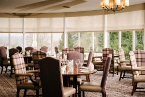 a dining room with tables and chairs and windows at Macdonald Forest Hills Hotel & Spa in Aberfoyle
