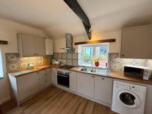 a kitchen with a sink and a washing machine at Polrunny Farm Seaberry Cottage with a sea view and log burner in Boscastle