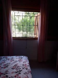 - une chambre avec une fenêtre et un lit avec une couverture fleurie dans l'établissement Villa Giusy, à Campomarino