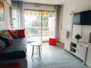 ein Wohnzimmer mit einem Sofa und einem Tisch in der Unterkunft logement climatisé à Juan les Pins dans résidence avec piscine in Juan-les-Pins