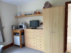 a room with a desk with a microwave and a television at Whidlecombe Farm in Priston