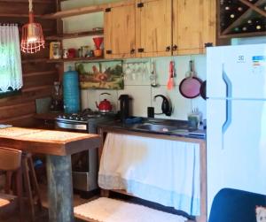 a kitchen with a white refrigerator and a table at Chalé de Toras in Campo Alegre