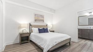 een witte slaapkamer met een bed en een wastafel bij Landing Modern Apartment with Amazing Amenities (ID7588X22) in Fort Myers