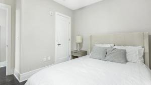 a white bedroom with a white bed and a lamp at Landing Modern Apartment with Amazing Amenities (ID1239X428) in Richmond