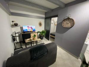 uma sala de estar com um sofá e um relógio na parede em Chez William et Elisa em Jonzac