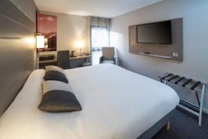a hotel room with a bed and a flat screen tv at Best Western Voiron Centre in Voiron