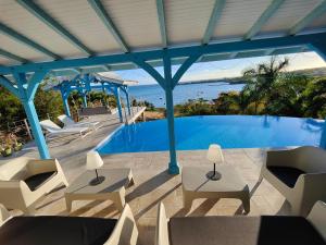 un patio con sillas y una piscina en Villa Nadia - Prestige et Confort Absolu avec Vue Imprenable sur la Mer, en Le Diamant