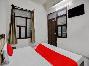 a bedroom with a red and white bed and windows at OYO Flagship Hotel Royal Choice in Rohtak