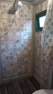 y baño con ducha y pared de azulejos. en Chalé Cafofo en Campo Alegre
