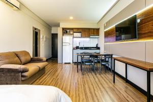 une cuisine et un salon avec un canapé et une table dans l'établissement Studio em condomínio c/ piscina 700m praia STI210, à Florianópolis