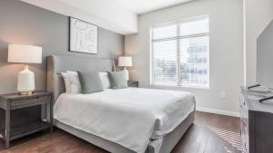 een witte slaapkamer met een bed en een raam bij Landing Modern Apartment with Amazing Amenities (ID8003X42) in Orlando