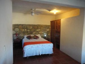 a bedroom with a bed and a stone wall at Casa Luna Playa in Puerto Ángel