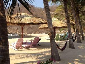 a group of chairs and umbrellas on a beach at Casa Luna Playa in Puerto Ángel