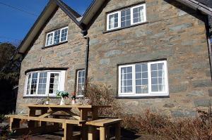 a stone house with a wooden table in front of it at Minafon near Barmouth in Llanaber