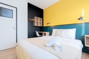 a bedroom with a large white bed with a yellow wall at Marcq-en-Baroeul - Beautiful apartment Art-déco ! in Marquette-lès-Lille +9 photos