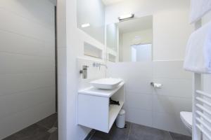 a white bathroom with a sink and a mirror at einzigartig - Das kleine Hotel im Wasserviertel in Lüneburg
