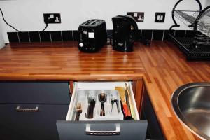 a kitchen counter with a drawer filled with cooking utensils at Modern City Central Studio APT in Birmingham
