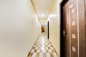 un long couloir avec un sol et des portes en damier dans l'établissement Super OYO Royal Continental, à New Delhi