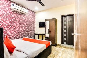 - une chambre avec un lit et un mur rouge dans l'établissement Super OYO Royal Continental, à New Delhi