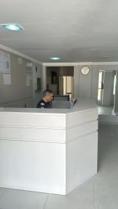 a man standing at a counter in an office at Hotel San Carlos in Balneário Camboriú