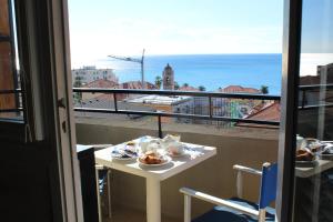 una mesa con comida en el balcón con vistas al océano en Hotel Palace, en Varazze