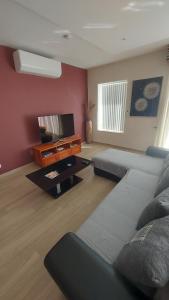 a living room with a couch and a tv at Trilogy, Ample Penthouse, Gozo in Kerċem