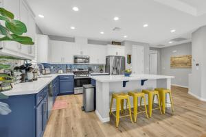 a kitchen with blue and white cabinets and yellow stools at Modern-fully Loaded-ev Charger-big Yard-10 Min Dt in West Sacramento