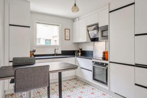 cocina con armarios blancos y mesa en Nice house with garden in Versailles - Welkeys, en Versalles