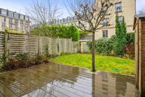 une arrière-cour avec une clôture et un arbre dans l'établissement Nice house with garden in Versailles - Welkeys, à Versailles