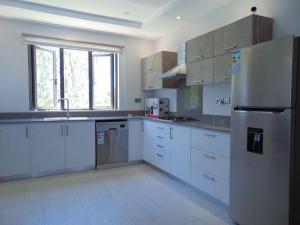 Spacious 3-Bedroom Apartment near Pereybere Beach في بيريبير: مطبخ مع دواليب بيضاء وثلاجة
