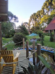 a wooden deck with a pond and a blue umbrella at Chalé Cafofo in Campo Alegre