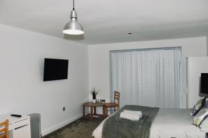 a bedroom with a bed and a table and a television at Modern City Central Studio APT in Birmingham