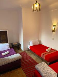 a room with two beds and a table at Hotel Dar El Qdima in Essaouira