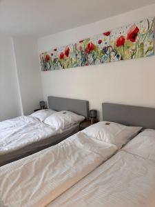 two beds in a room with a painting on the wall at Apartment für 6 Aalen Zentrum Netflix 300 Mbit Wlan in Aalen