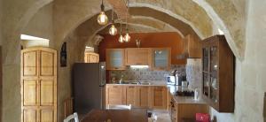 a kitchen with wooden cabinets and a black refrigerator at Tas-Suplu Farmhouse in San Lawrenz