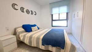 ein weißes Schlafzimmer mit einem Bett mit einer blauen Decke in der Unterkunft Cancún Portaventura Familidays in Salou