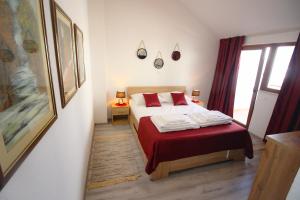 a bedroom with a bed with red sheets and a window at Villa Deny Mostar in Mostar