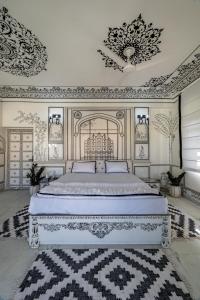 Schlafzimmer mit einem großen weißen Bett und verzierten Decken in der Unterkunft Lalluji Luxe in Jaipur