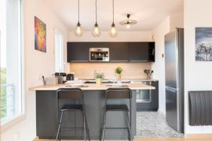 a kitchen with a island with two bar stools at Beautiful apartment equipped near train parking in Lille +15 photos