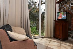 sala de estar con sofá, TV y ventana en Le BASTIDON de CHANTE PIERRE, en Cuers